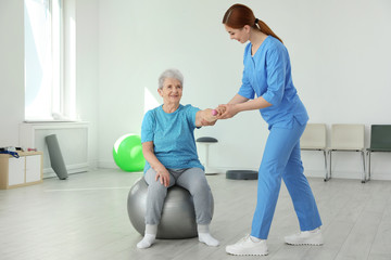 Sticker - Professional physiotherapist working with elderly patient in rehabilitation center