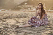 Happy Brunette Woman Sitting In The Beach At Golden Hour