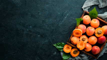 Fresh apricots with green leaves in a box. Rustic style. Top view. Free space for your text.