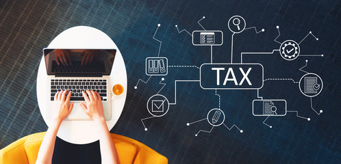 Wall Mural - Tax theme with person using a laptop on a white table