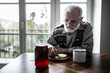 © Photographee.eu - Senior grandfather with grey hair and beard sitting alone in the kitchen eating breakfast