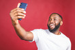 © denis_vermenko - Say cheese. Close up of young beautiful dark-skinned black man in casual smiling with teeth, holding smartphone, making selfie photo.
