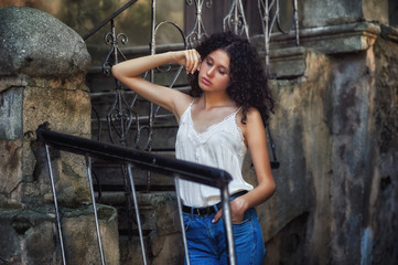 Portrait of a young girl in the city . Slim model in jeans and light blouse