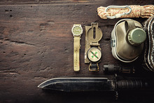 Military Tactical Equipment For The Departure. Assortment Of Survival Hiking Gear On Wooden Background. Top View - Vintage Film Grain Filter Effect Styles