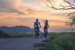 couple lover biker cyclist riding enjoyment to the field of meadow lake at sunset, adventure bicycle wild and journey activity.