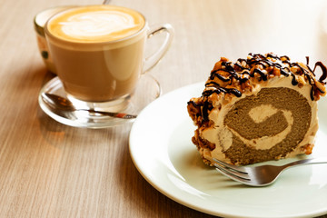 Hot latte and roll cake on a wooden table