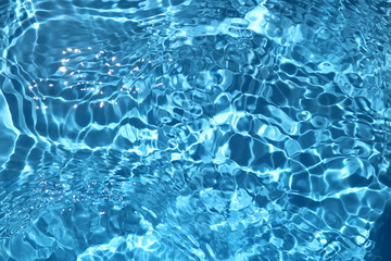 blue and bright water surface with sun refection in swimming pool for background
