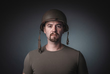 Portrait Of A Man In A T-shirt Wearing A Soldier's Military Helmet,