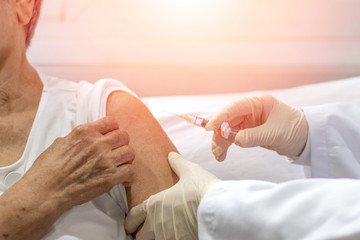 Wall Mural - Senior vaccination concept. Elderly getting immune vaccine at arm for flu shot, pneumonia, and shingles(MMR) in hospital by nurse. Doctor giving an injection to older people patient in clinic.