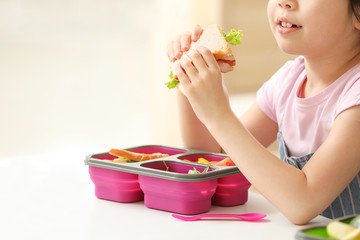 Poster - Little schoolgirl eating tasty lunch in classroom