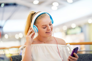 Portrait of a happy girl listening music on line with wireless headphones from a smartphone. Happy teen listening to the music. Beautiful young woman listening to music in headphones with smartphone.