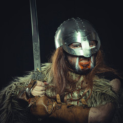 War, Viking, Scandinavian warrior with helmet and war paintings, wears a sword and a cape of animal skin