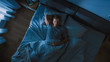 © Gorodenkoff - Top View of Handsome Young Man Sleeping Cozily on a Bed in His Bedroom at Night. Blue Nightly Colors with Cold Weak Lamppost Light Shining Through the Window.