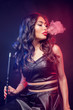 Young, beautiful woman in the night club or bar smoke a hookah or shisha