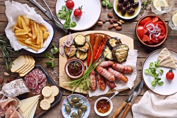 Grill party table concept with grilled sausage, potato fries,vegetable,sappetizers and tomato salad. Summer outdoor dinner table .