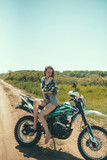 Fototapeta  - Young beautiful girl posing sitting on a motorcycle outdoors