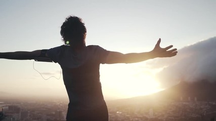 Wall Mural - Male athlete out stretching his hands against sunrise