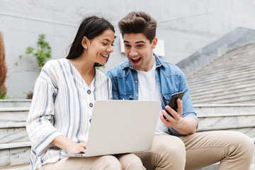 Canvas Print - Amazing loving couple business people colleagues outdoors outside using mobile phone and laptop computer.