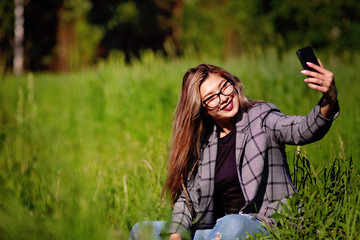 Wall Mural - Young beautiful asian girl makes selfie in the grass in summer