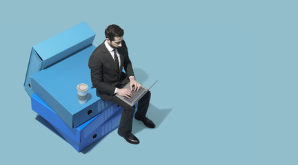 Wall Mural - Miniature corporate businessman working with his laptop