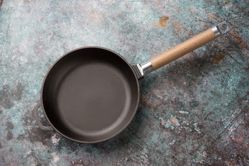 Wall Mural - Empty cast iron frying pan on dark green culinary background, view from above