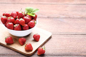 Wall Mural - Fresh strawberries in bowl on brown wooden table