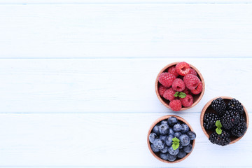 Wall Mural - Ripe and sweet fruits in bowls on white wooden table