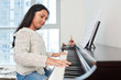 Indian young girl sitting at piano and learning to play on it at musical school