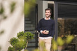 © Westend61 - Young man leaning in door of his house, with a cup of coffee