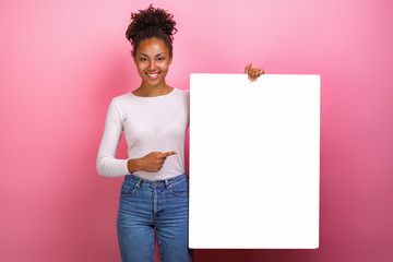 Wall Mural - Studio shot of a happy girl pointing for empty white paper sheet copyspace- Image