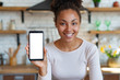 © speed300 - Young smiling woman sits and showing a mockup with white screen of cell telephone . - Image