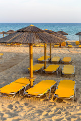 Sandy beach with sunbeds and umbrellas on an summer evening (Peloponnese, Greece)