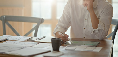 UI UX designer planning application prototype wireframe on tablet and paperwork layout