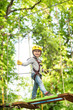 © Volodymyr - Toddler kindergarten. Active children. Balance beam and rope bridges. Toddler age. Cute child boy. Rope park - climbing center. Helmet and safety equipment.