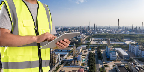 Wall Mural - worker working on pad with oil and gas refinery background,Smart factory concept.