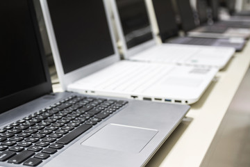 A row of laptops in computer shop. Closeup, selective focus