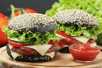 Two black burgers with vegetables and beef meat	