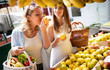 © NDABCREATIVITY - Young women friends baying vegetables and fruits on the market