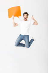 Poster - Emotional excited young man posing isolated over white wall background holding speech bubble.