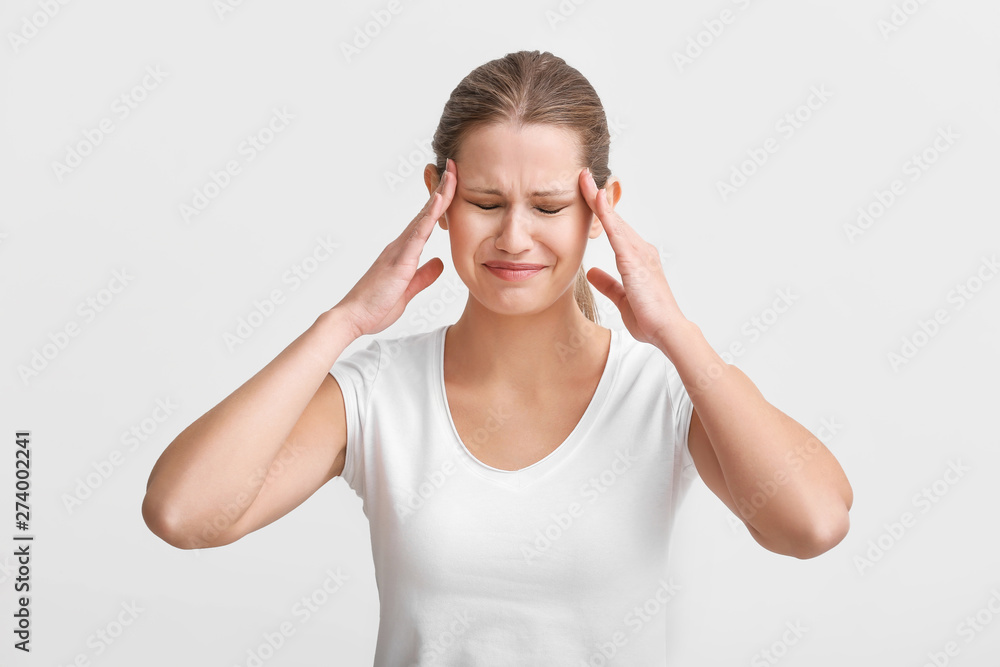 Young woman suffering from headache on white background