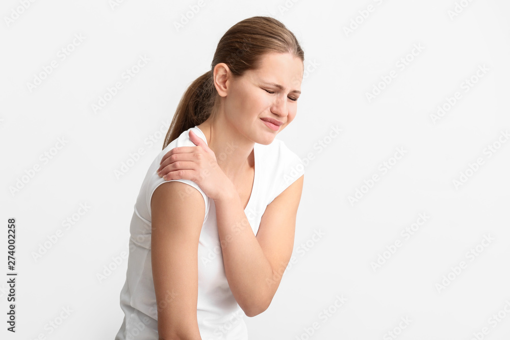 Young woman suffering from pain in shoulder on white background