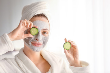 Wall Mural - Young woman with clay mask and cucumber slices at home