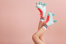 Legs Of Woman In Vintage Roller Skates On Color Background