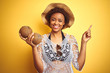 Young african american woman with afro hair holding coconut over yellow isolated background very happy pointing with hand and finger to the side