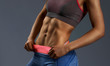 © serhiibobyk - Close up of woman's abs with tanned skin on gray background
