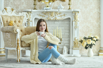 Portrait of beautiful teen girl with cup of tea sitting on floor