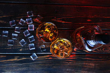 Wall Mural - Two glasses of whiskey with ice cubes served on wooden planks.