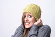 © sharplaninac - Portrait of freezing young woman with yellow beanie covering head on cold winter weather on light gray background.