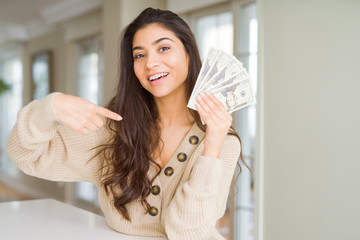 Wall Mural - Young woman holding 20 dollars bank notes with surprise face pointing finger to himself