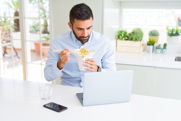 Wall Mural - Business man eating asian food from delivery while working using computer laptop at the office